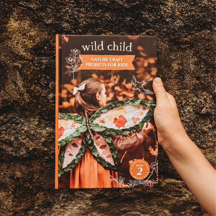 Book titled 'Wild Child: Nature Craft Projects for Kids' held by a hand against a textured brown background