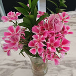 A bouquet of pink flowers in a clear vase on a marble table