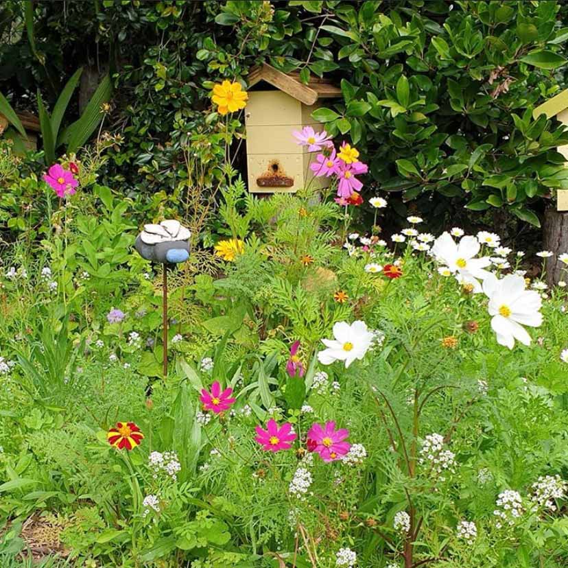 A bee hive surrounded by meadow flowers and lush greens